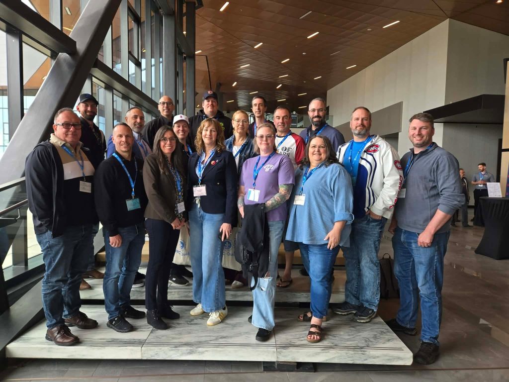 A group of UNDE members wearing conference lanyards, posed together indoors